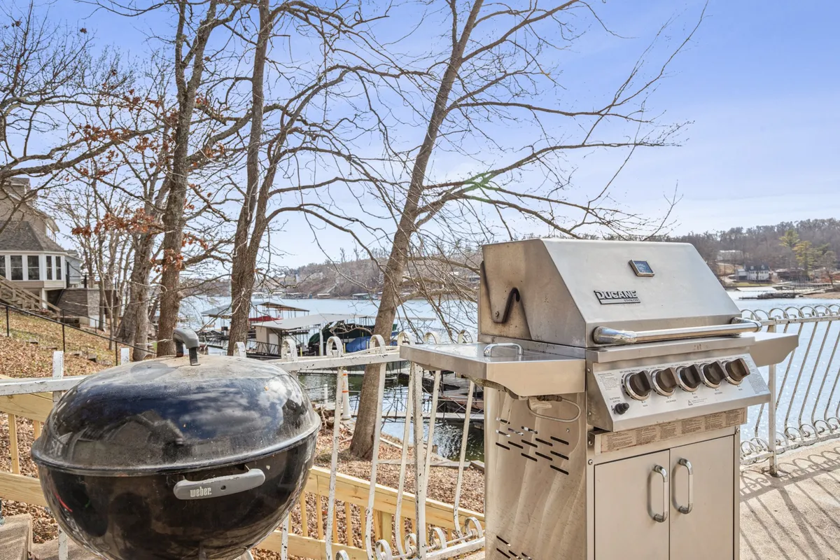 A lakeside deck is shown with a prominent grill, comfortable seating, and picturesque views of the surrounding trees and water. The mood is leisurely, capturing the spirit of outdoor dining, relaxed mornings, and festive barbecues.